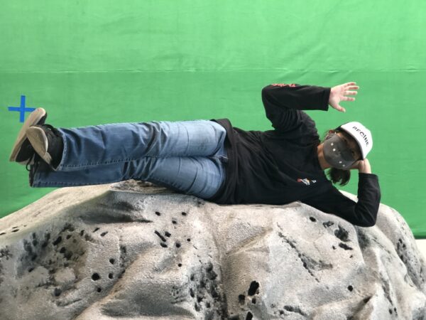 Director Toy Lei posing  on one of the moon rocks in front of a green screen on the set of Moon the film. 